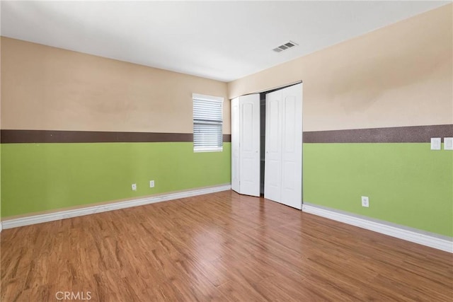 unfurnished bedroom featuring baseboards, visible vents, and wood finished floors