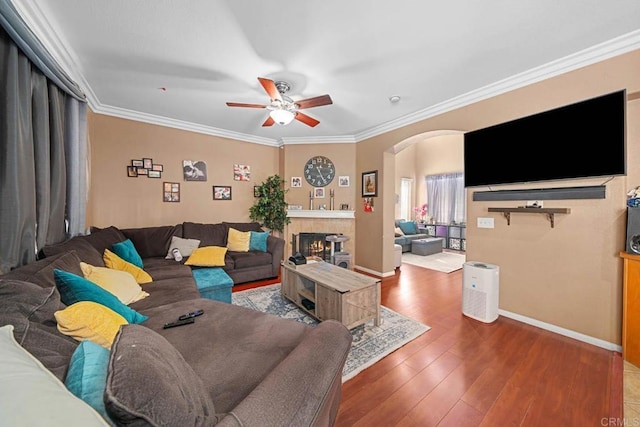 living room featuring ornamental molding, arched walkways, a tile fireplace, and hardwood / wood-style flooring