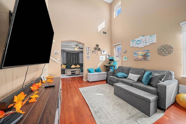 living room with ceiling fan, visible vents, arched walkways, and wood finished floors