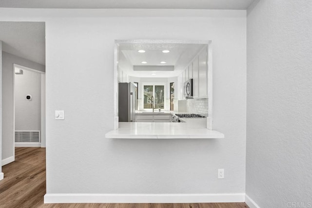 kitchen featuring tasteful backsplash, stainless steel appliances, wood finished floors, and light countertops