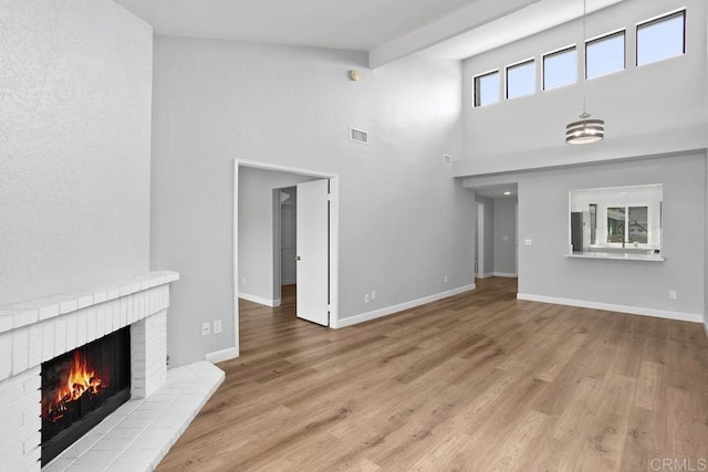 unfurnished living room featuring light wood-type flooring, baseboards, a fireplace, and visible vents