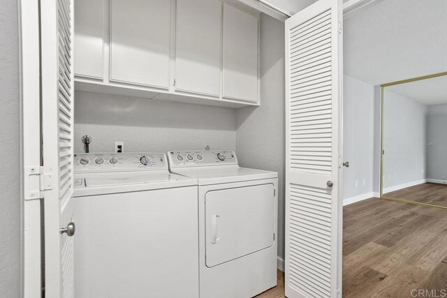 laundry area featuring cabinet space, baseboards, separate washer and dryer, and light wood finished floors