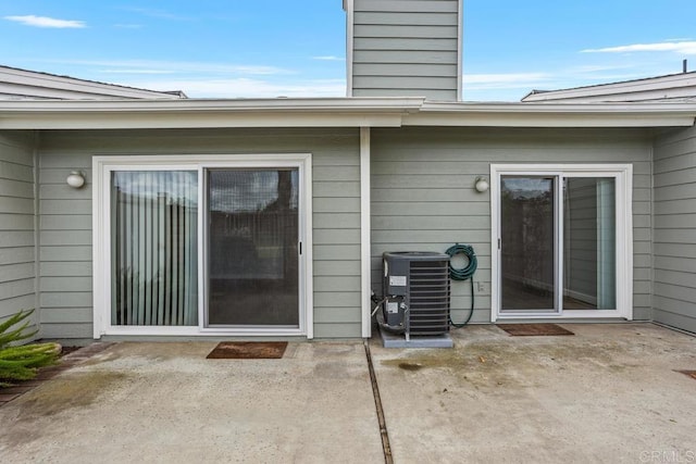 entrance to property with cooling unit, a patio area, and a chimney