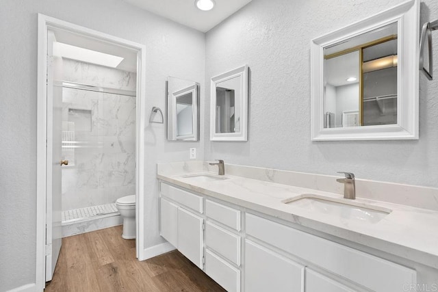 bathroom with wood finished floors, a stall shower, a sink, and toilet