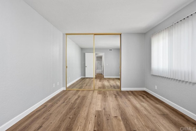 empty room with visible vents, baseboards, and wood finished floors