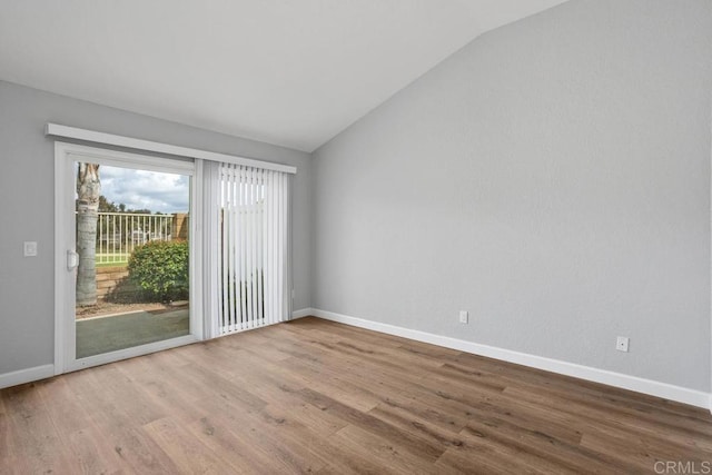 unfurnished room featuring lofted ceiling, baseboards, and wood finished floors