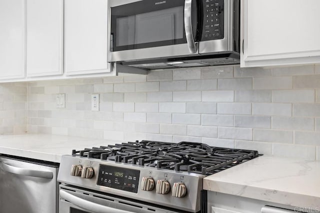 kitchen featuring stainless steel appliances, decorative backsplash, light stone countertops, and white cabinets