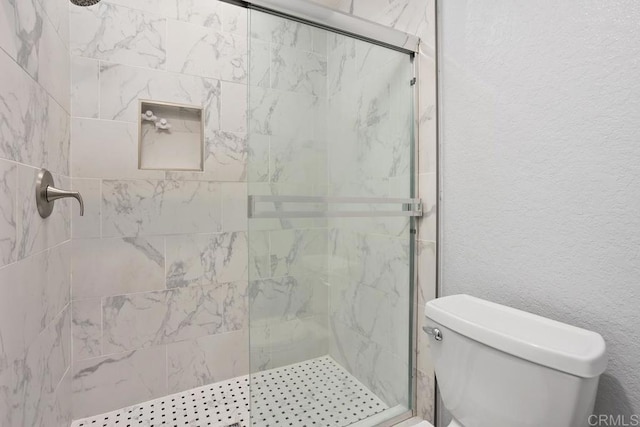 full bathroom with toilet, a shower stall, and a textured wall