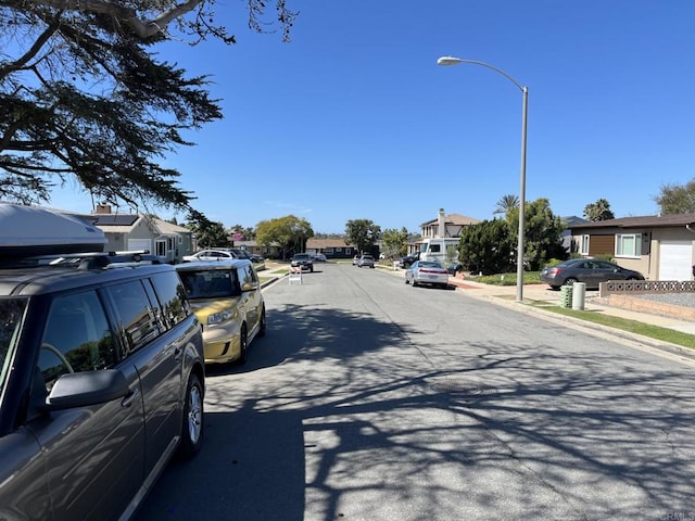 view of road with sidewalks, a residential view, street lights, and curbs