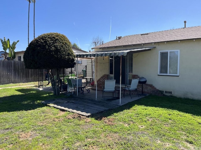 exterior space with a yard, fence, a shingled roof, and stucco siding