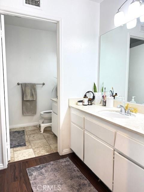 bathroom featuring visible vents, toilet, vanity, and wood finished floors