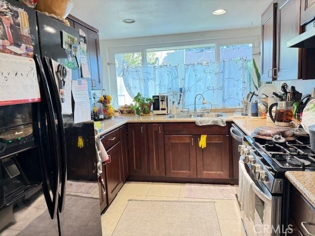 kitchen with plenty of natural light, range hood, stainless steel range with gas cooktop, and a sink