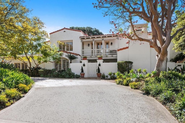 mediterranean / spanish-style house with a fenced front yard, stucco siding, driveway, and a gate