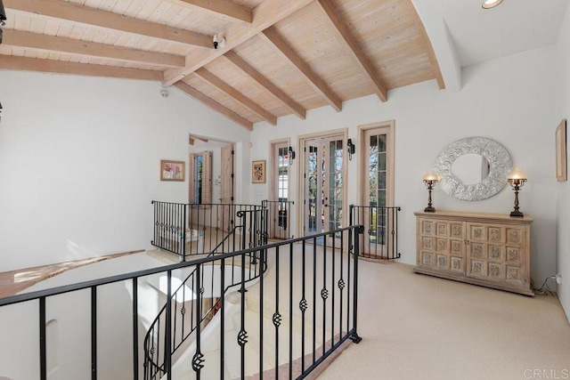 hall with an upstairs landing, wood ceiling, lofted ceiling with beams, and carpet