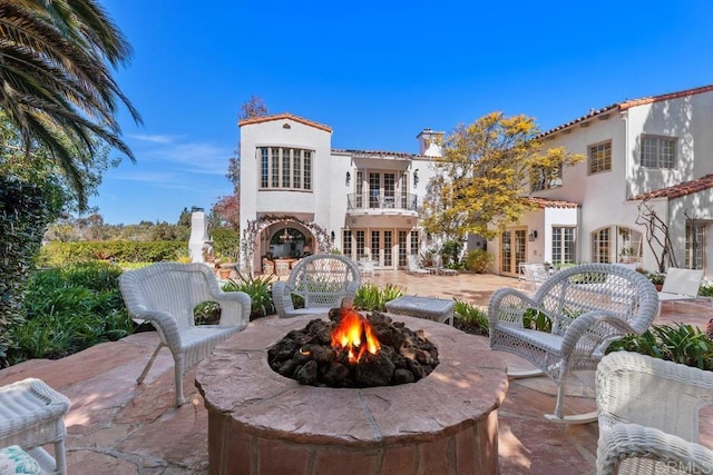 rear view of house with french doors, a patio, a balcony, and stucco siding