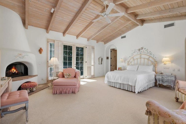 carpeted bedroom featuring access to exterior, visible vents, arched walkways, and a fireplace