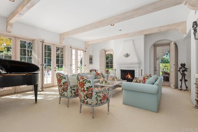 carpeted living area with french doors, beamed ceiling, a fireplace, and a healthy amount of sunlight