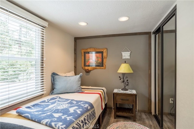 bedroom with recessed lighting, a textured ceiling, baseboards, and wood finished floors