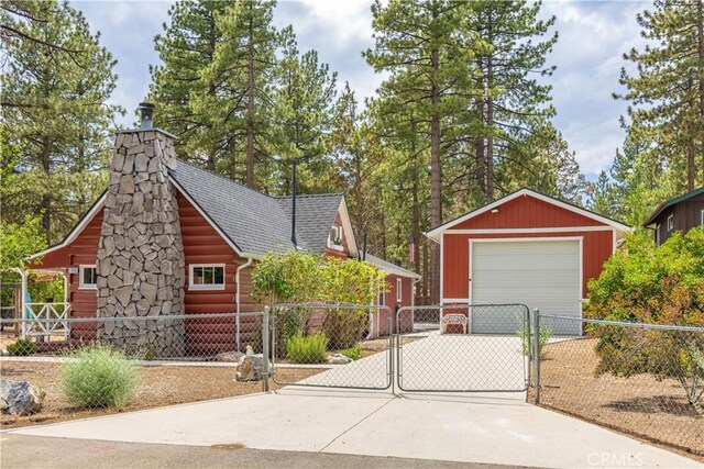 view of front of house with a garage, driveway, an outdoor structure, and fence