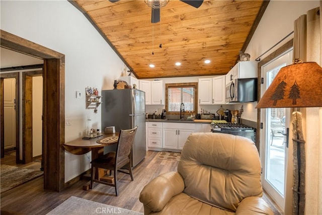 kitchen with lofted ceiling, appliances with stainless steel finishes, white cabinetry, a sink, and wooden ceiling