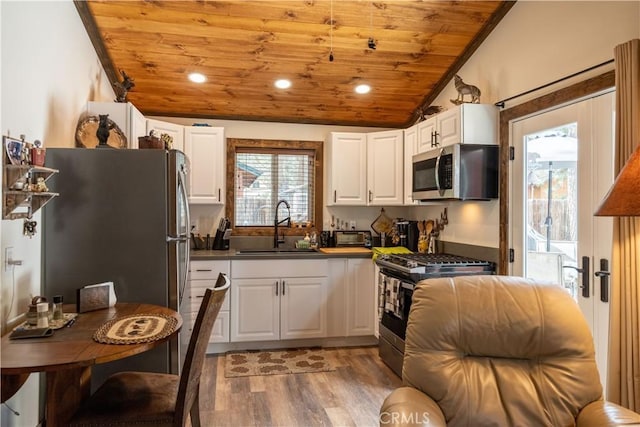 kitchen featuring lofted ceiling, a sink, wood ceiling, white cabinets, and appliances with stainless steel finishes