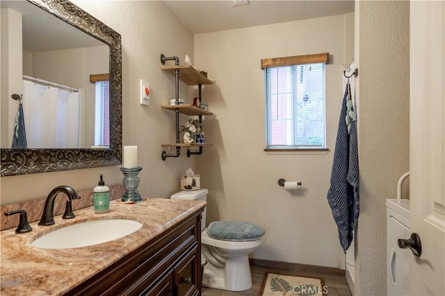 full bath with a textured wall, toilet, wood finished floors, vanity, and baseboards