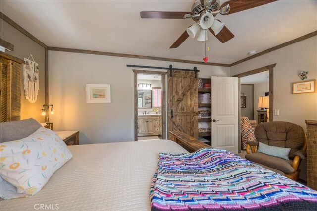 bedroom with ornamental molding, ceiling fan, a barn door, and ensuite bathroom