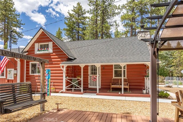 back of property featuring a chimney, log siding, roof with shingles, covered porch, and a pergola