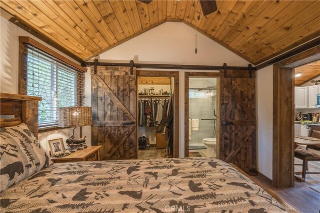 bedroom with wood ceiling, a barn door, and lofted ceiling