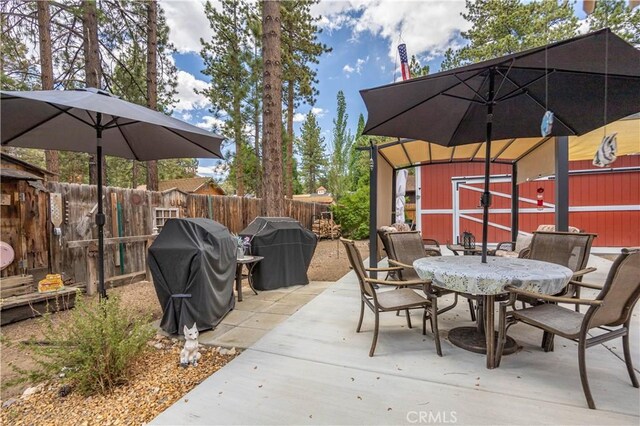 view of patio / terrace with an outbuilding, outdoor dining space, area for grilling, and fence