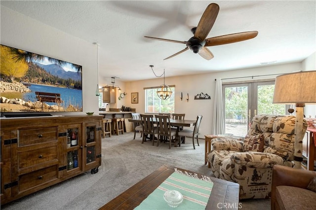 living area with a wealth of natural light, a textured ceiling, a ceiling fan, and carpet flooring