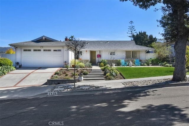 ranch-style home with a garage, a front yard, concrete driveway, and stucco siding