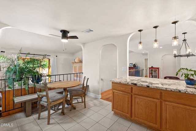 interior space featuring light tile patterned floors, visible vents, arched walkways, baseboards, and ceiling fan with notable chandelier