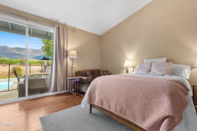 bedroom featuring vaulted ceiling, a mountain view, hardwood / wood-style flooring, and access to exterior