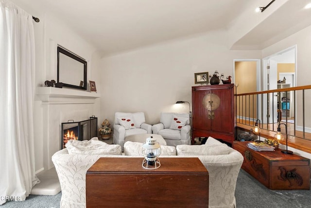 living area with a lit fireplace and carpet flooring