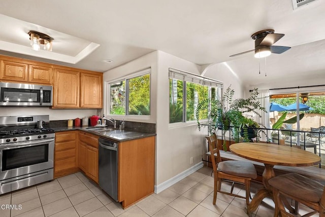 kitchen featuring appliances with stainless steel finishes, dark countertops, a sink, and a healthy amount of sunlight