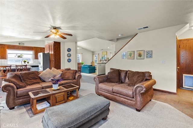 living area featuring light tile patterned floors, ceiling fan, lofted ceiling, visible vents, and baseboards