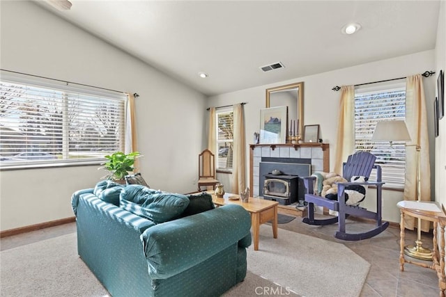 tiled living room with lofted ceiling, a wood stove, visible vents, and a healthy amount of sunlight