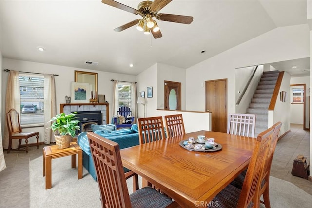 dining area featuring visible vents, ceiling fan, stairway, vaulted ceiling, and a fireplace