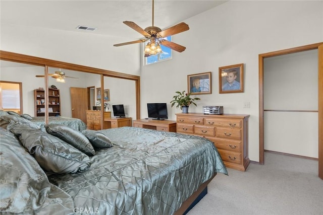 bedroom featuring a closet, light colored carpet, visible vents, ceiling fan, and high vaulted ceiling