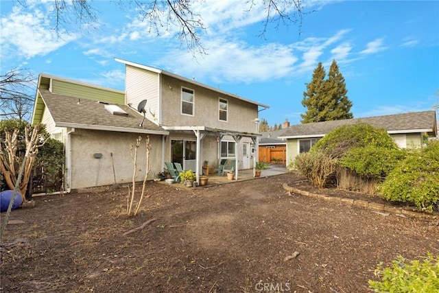 rear view of house with stucco siding, fence, a pergola, and a patio