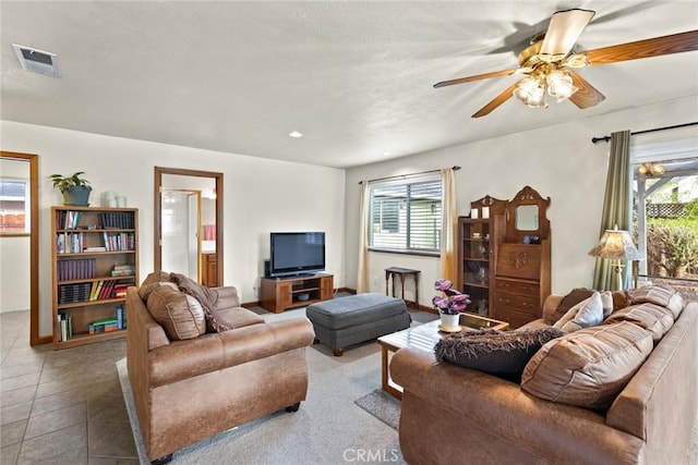 tiled living area with a healthy amount of sunlight, a textured ceiling, visible vents, and a ceiling fan