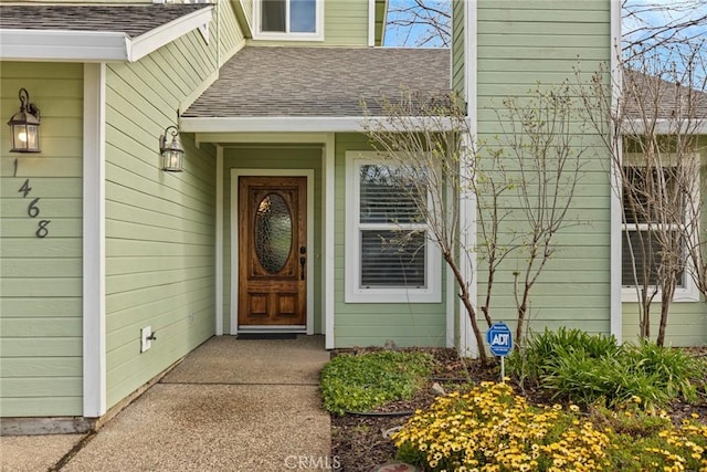 view of exterior entry with a shingled roof