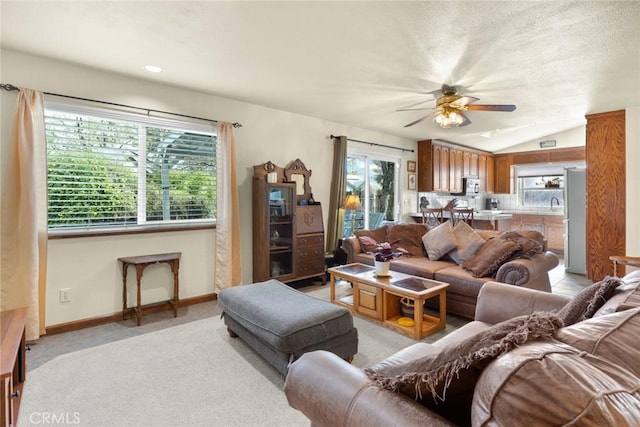 living room with ceiling fan, baseboards, lofted ceiling, and a healthy amount of sunlight