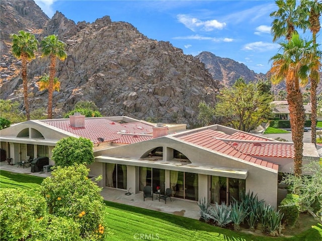 rear view of house featuring a patio, a tiled roof, a mountain view, and stucco siding