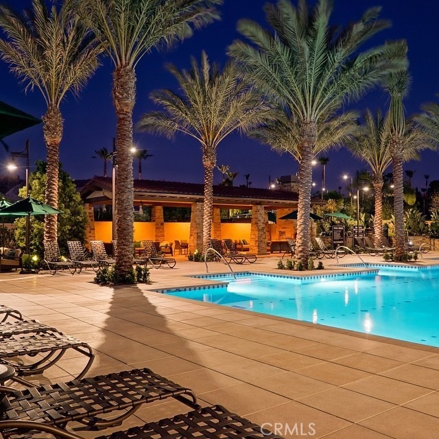 pool at twilight featuring a patio and a community pool