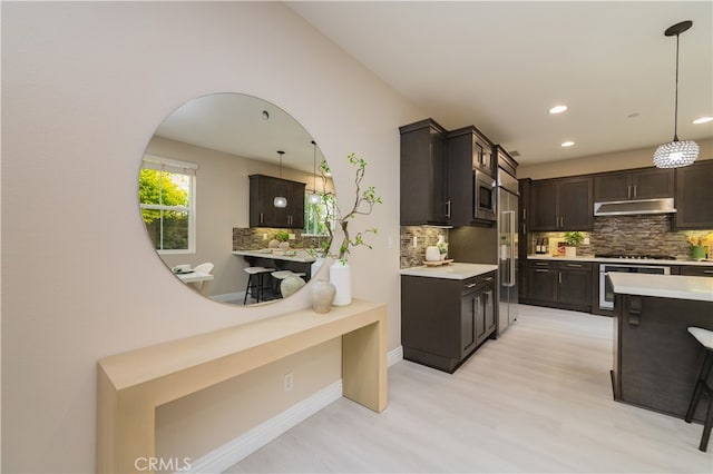 kitchen with dark brown cabinetry, under cabinet range hood, appliances with stainless steel finishes, and light countertops