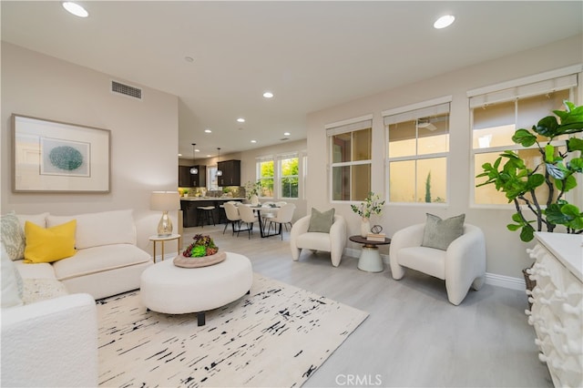 living area featuring light wood-style flooring, visible vents, baseboards, and recessed lighting