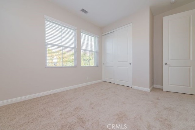 unfurnished bedroom with carpet floors, a closet, visible vents, and baseboards