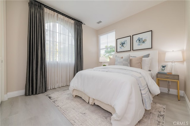 bedroom featuring wood finished floors, visible vents, and baseboards